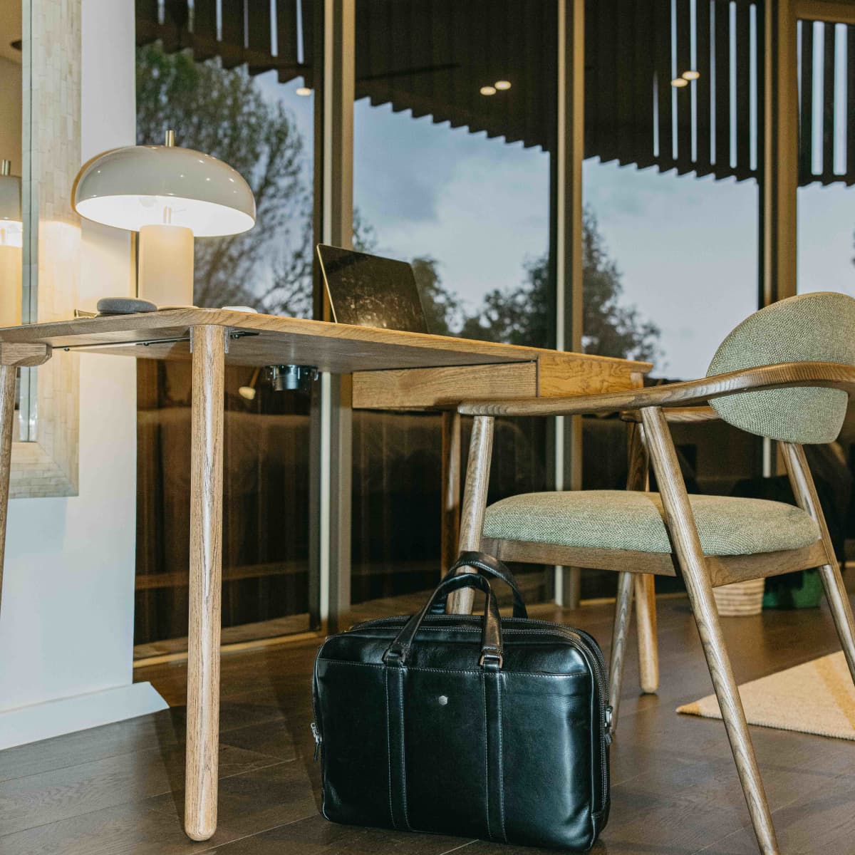 Black leather Laptop Briefcase on the floor beside a desk in a sunlit office