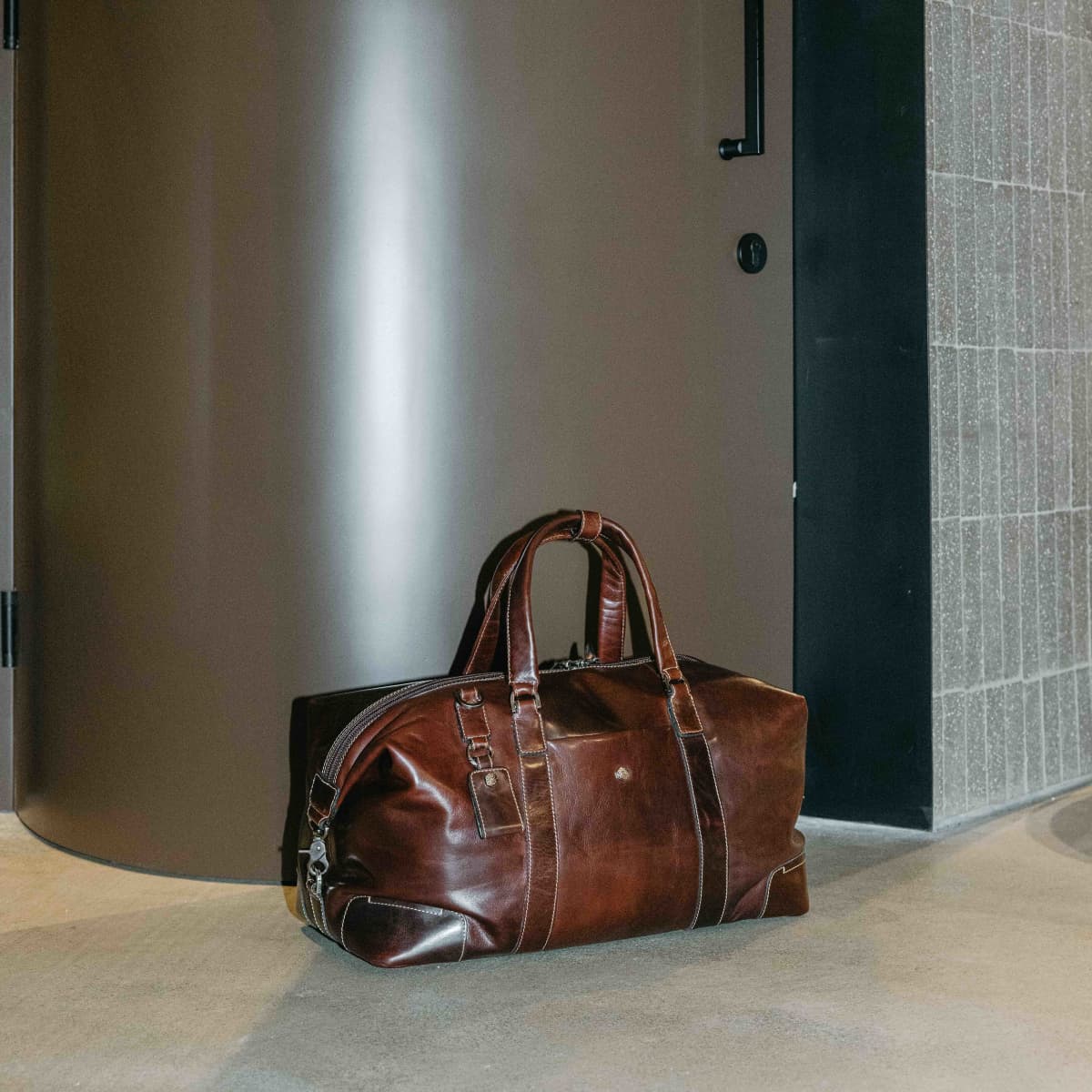Mocha leather Weekender on the floor in a modern hallway