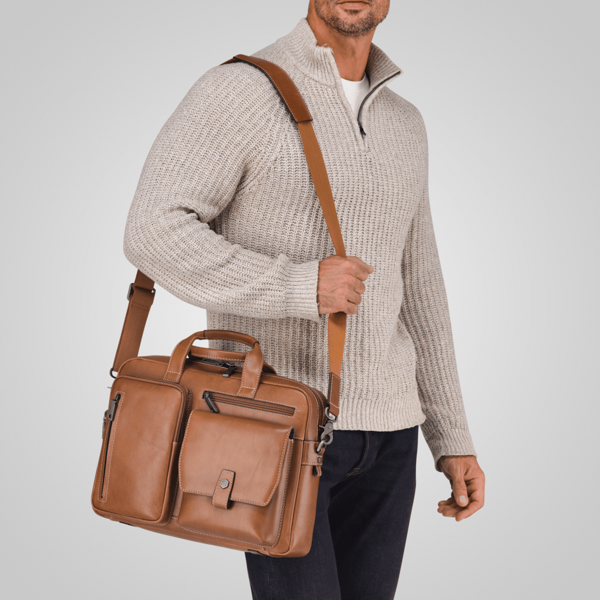 Man in a cream knit jumper wearing the Colt tan leather Laptop Briefcase on its shoulder strap