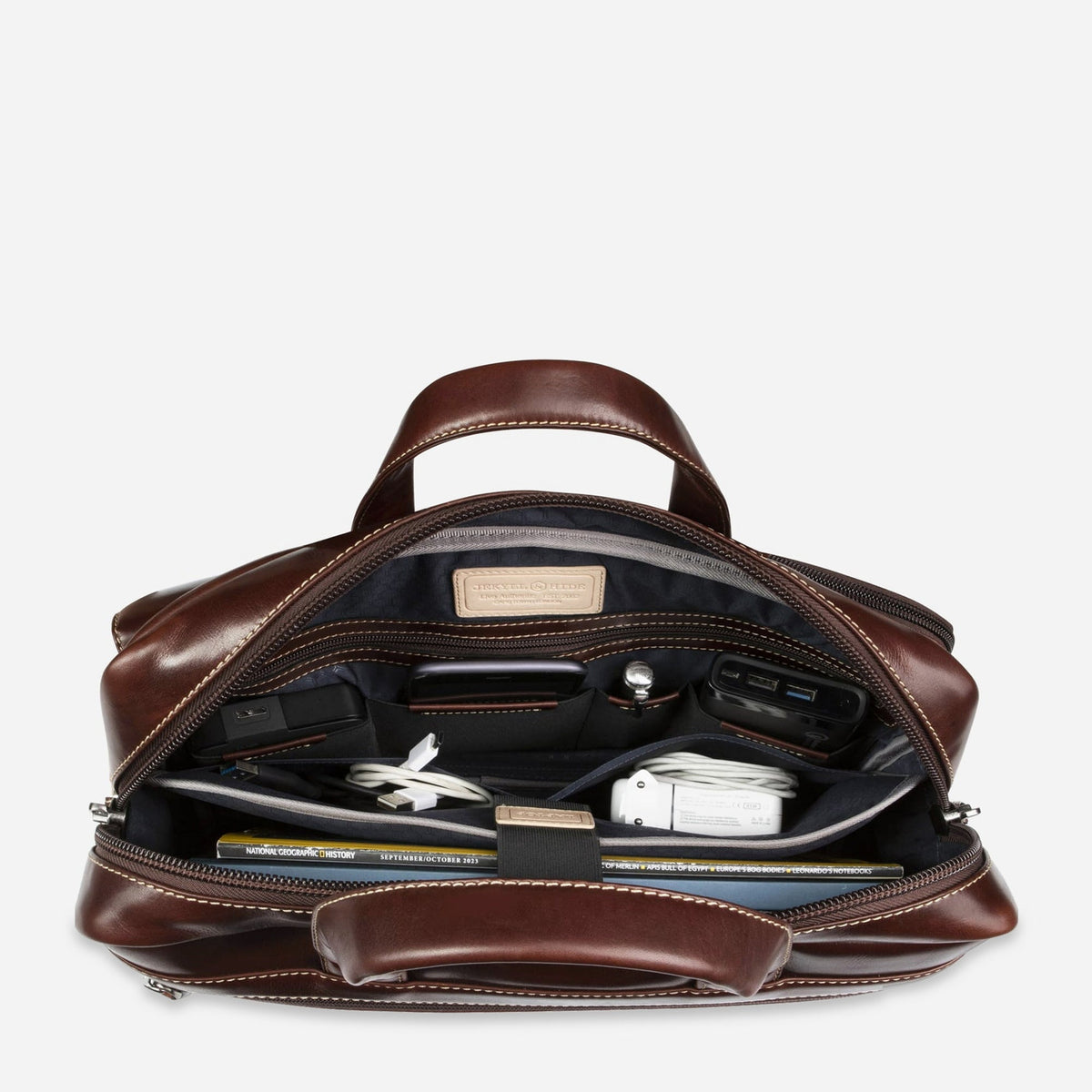 Mocha leather Laptop Briefcase open from above, showing organiser pockets holding a tablet, cables and charger