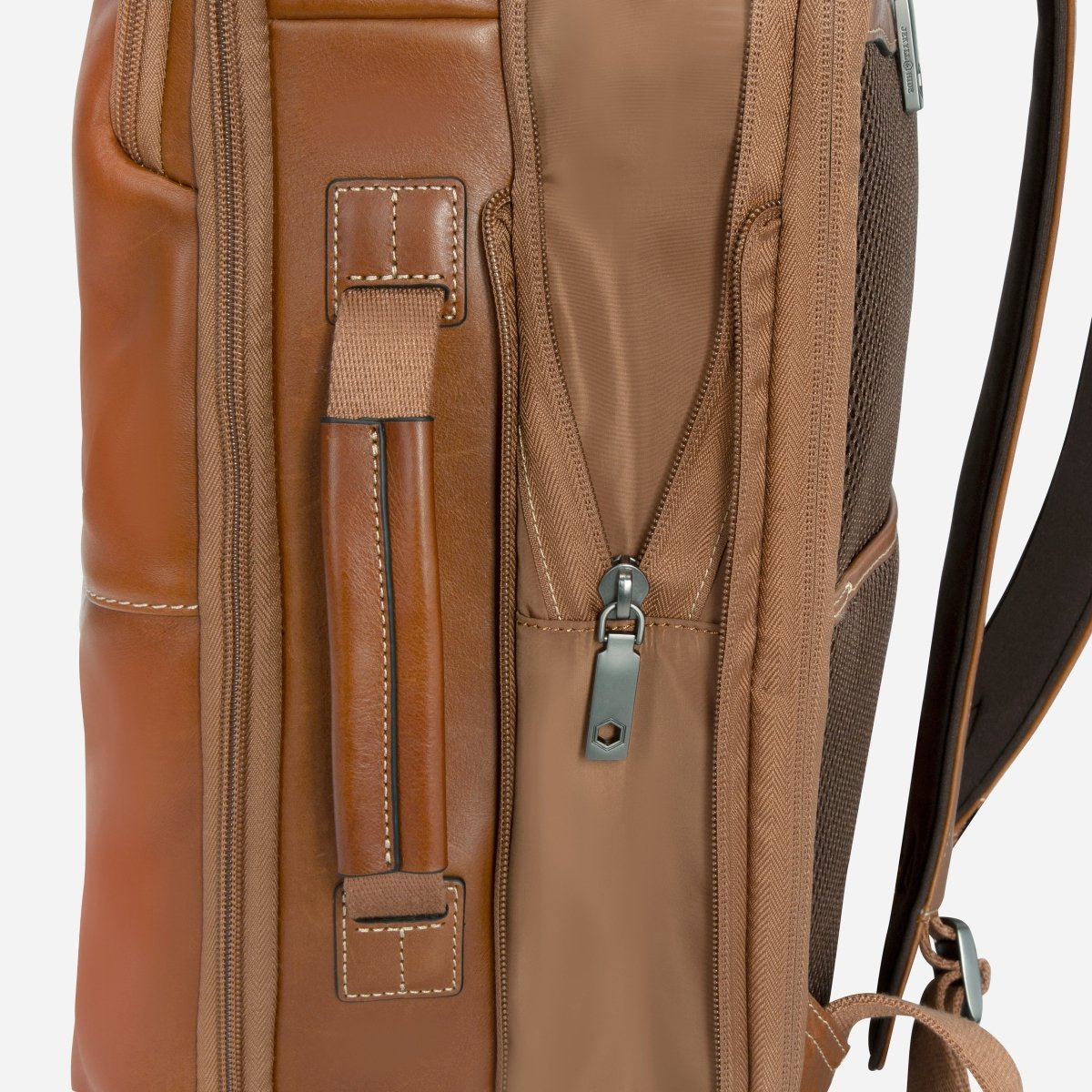 Close-up of the tan leather backpack's side carry handle and expander zip – Jekyll & Hide