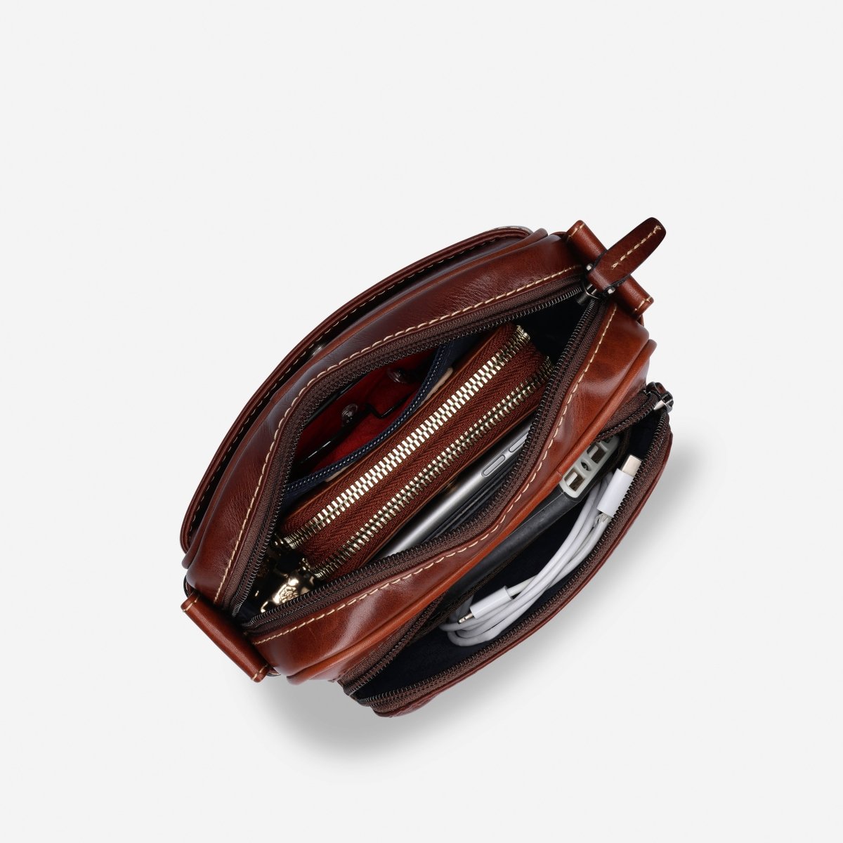 Mocha Crossbody Bag unzipped from above, holding a purse and cables