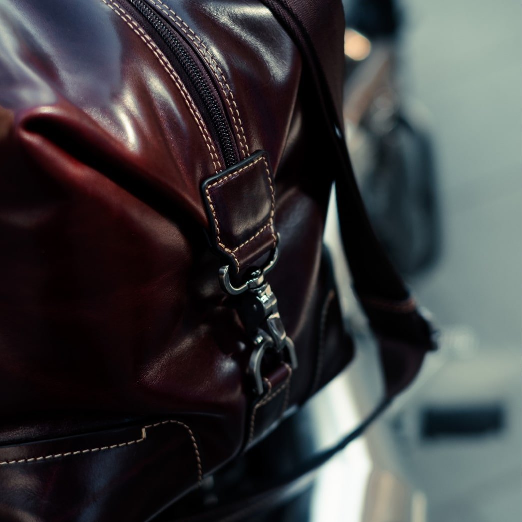 Close-up of the Mocha Weekender's stitched strap tab and swivel clip