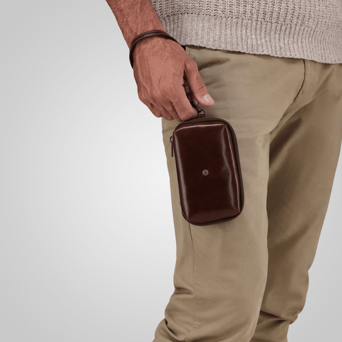 Man carrying the Mocha leather Cable Pouch by its wrist strap