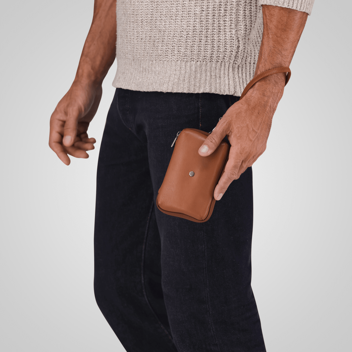 Man carrying the tan leather Cable Pouch by its wrist strap