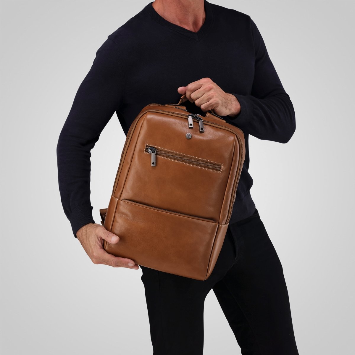 Man holding the tan leather laptop backpack by the top handle – Jekyll & Hide