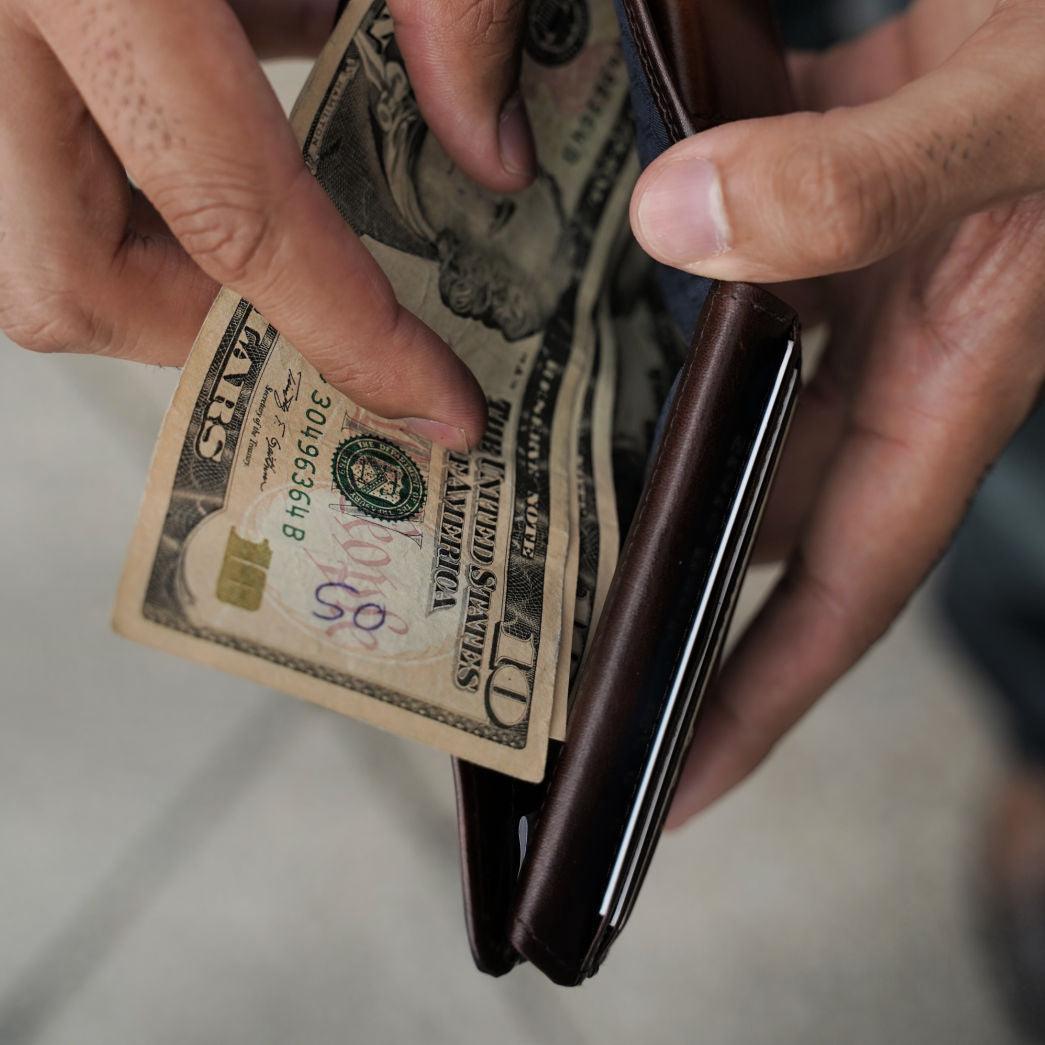Hands taking banknotes from a brown leather Jekyll & Hide bifold wallet
