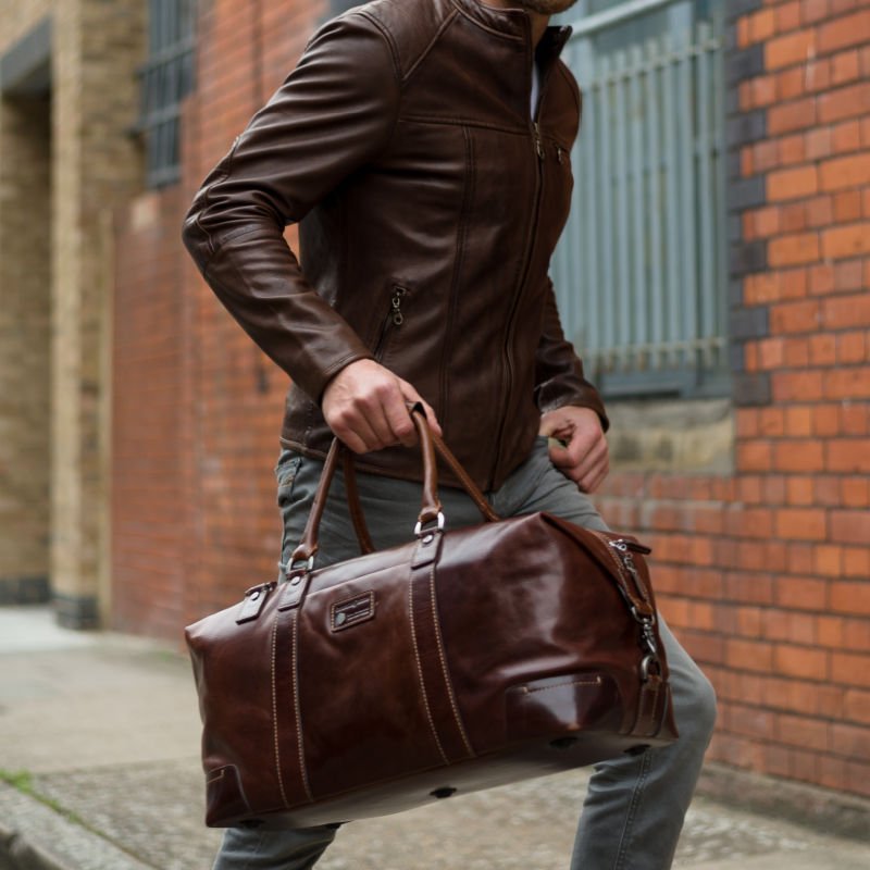 Man in a brown leather jacket carrying the Mocha Weekender by its handles