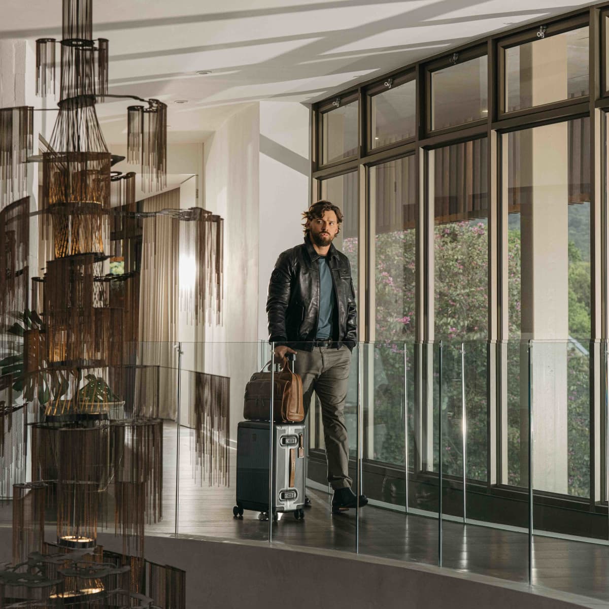 Man standing in a hotel atrium with the silver Carry-On suitcase