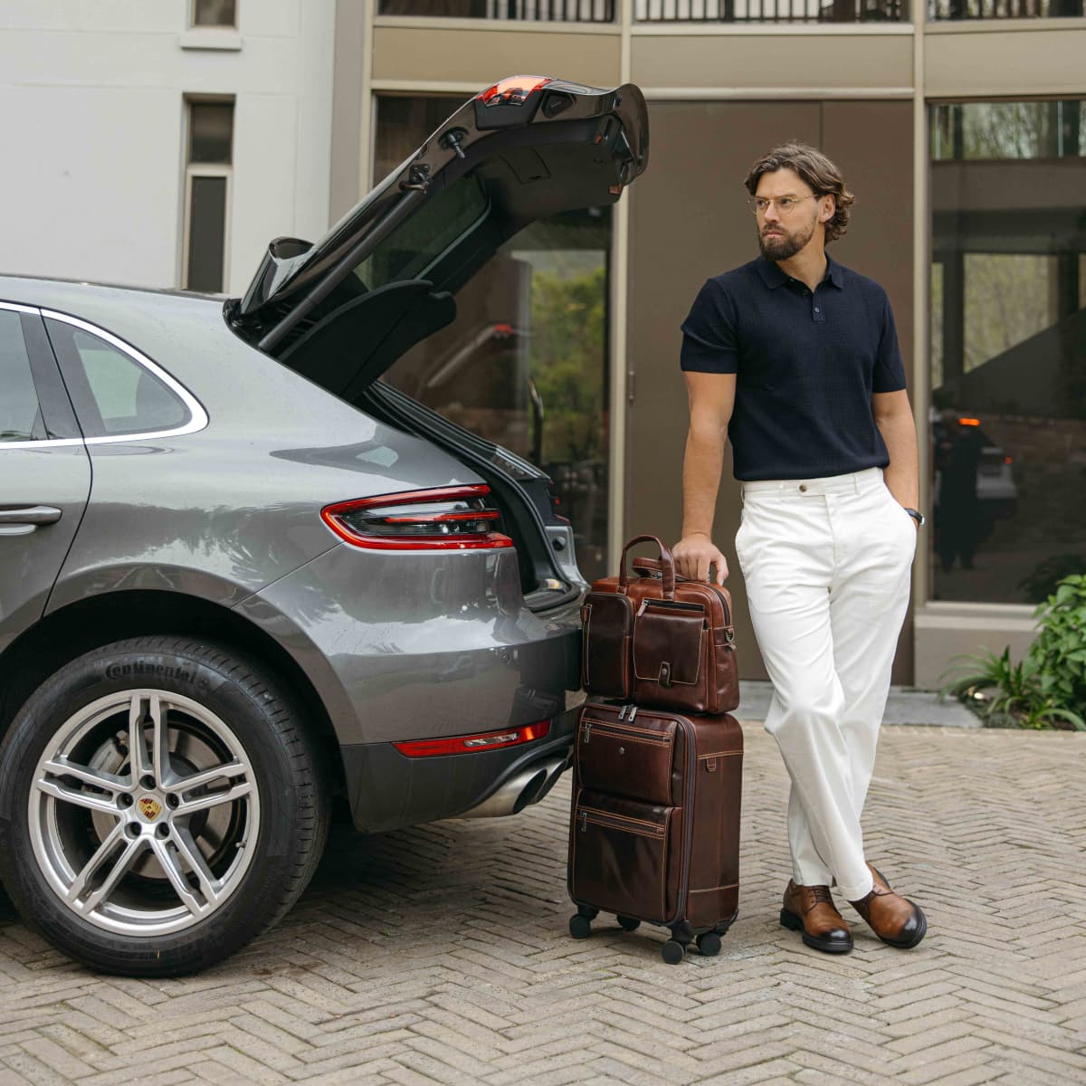 Man standing by an open car boot with the Mocha leather Laptop Briefcase on his suitcase