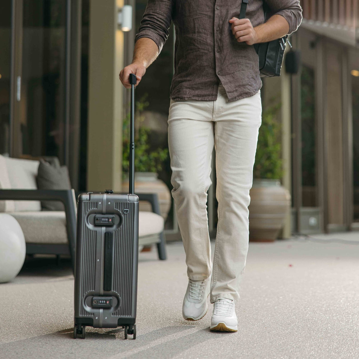 Man wheeling the Jekyll & Hide graphite-black Carry-On suitcase across a hotel terrace