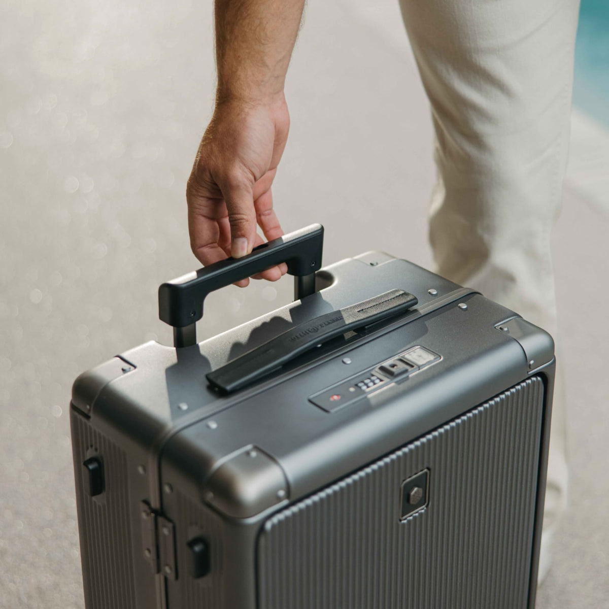 Lifting the Jekyll & Hide graphite-black Carry-On by its top handle, showing the TSA combination lock