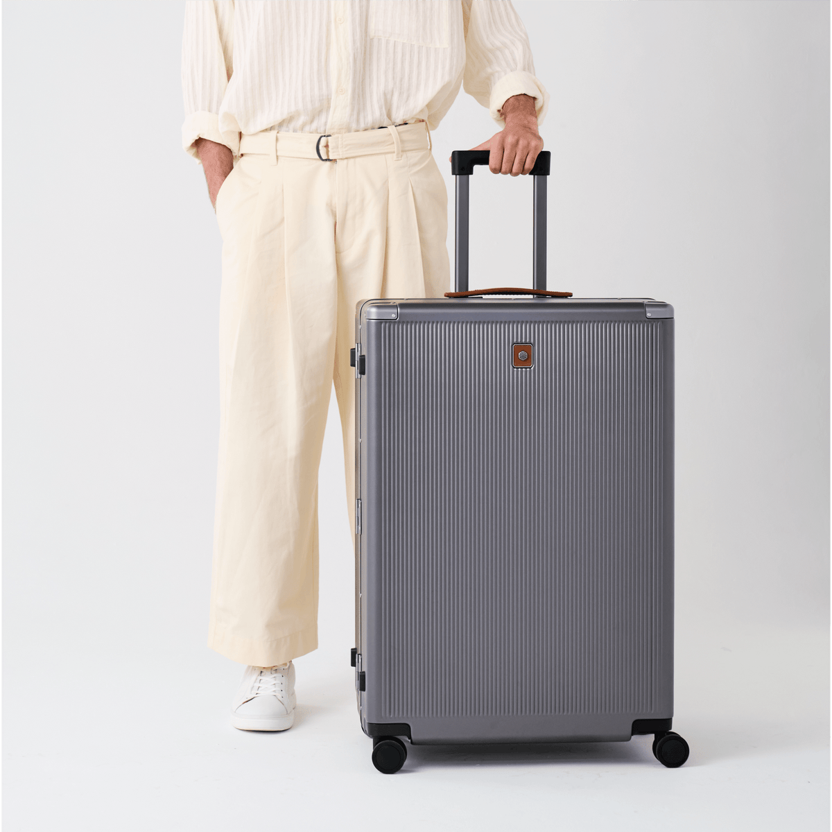 Man in cream trousers wheeling the Jekyll & Hide Large Check-In suitcase